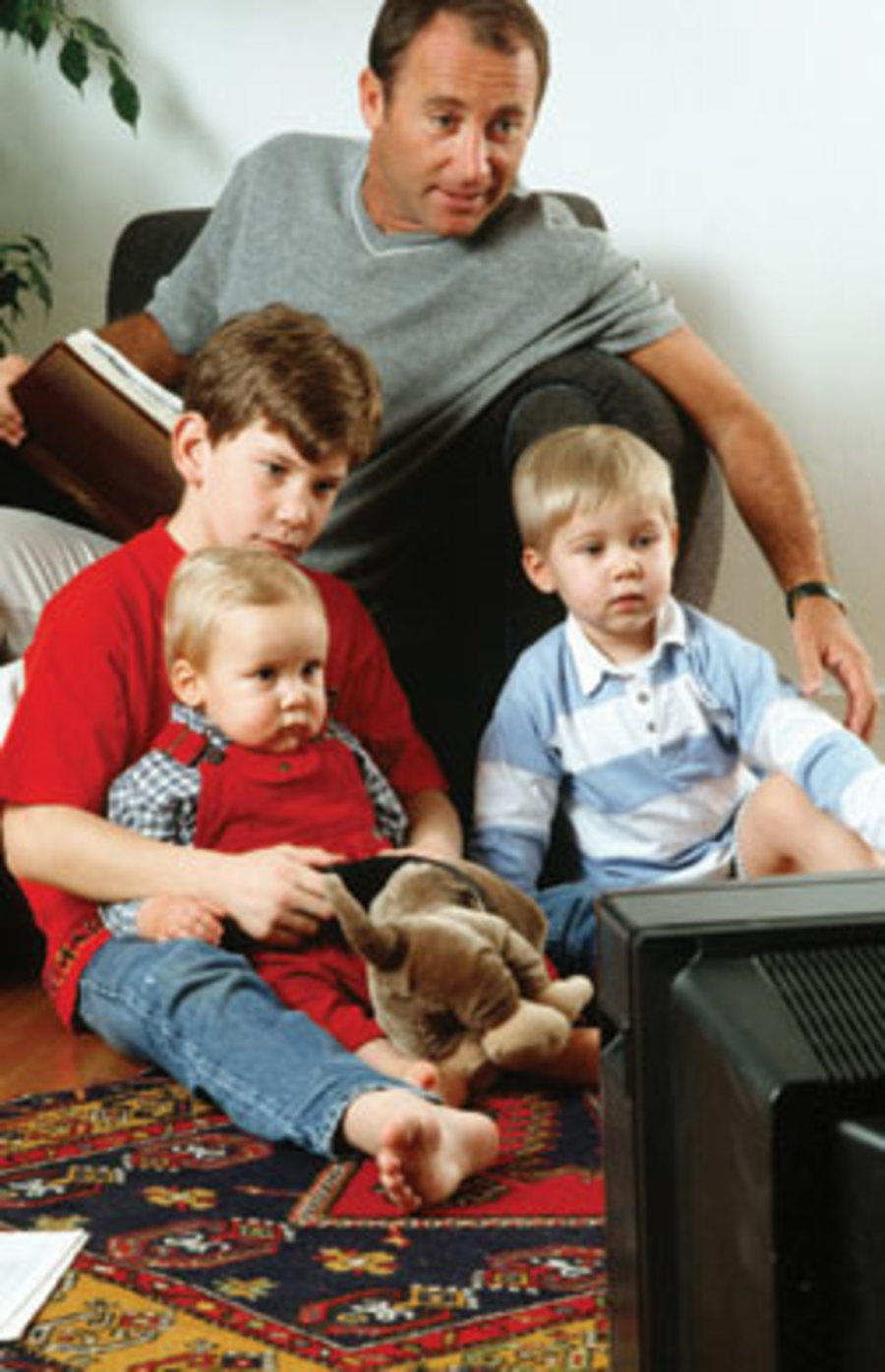 man watching tv with his three boys