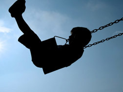silhouette of boy swinging on a swing