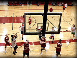 looking down at a basketball court as a man tries to shoot a basket.