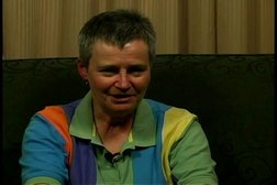 A woman with short hair sits on a couch.